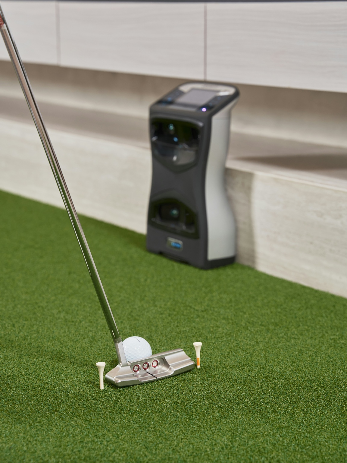 Portable indoor golf setup with putter, ball, and compact launch monitor